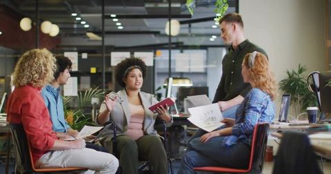 Woman in wheelchair leading collaborative team meeting presenting charts in modern office