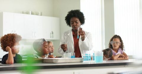 Black stem teacher in lab coat conducting chemistry demo with diverse elementary students