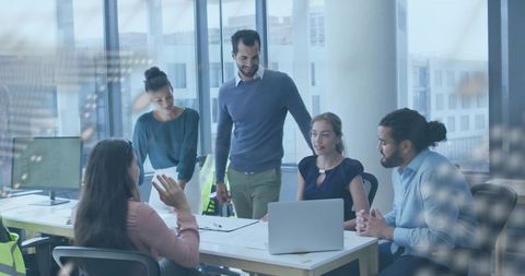 Team collaborating with laptops and documents in modern office