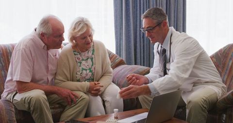 Senior couple consulting doctor at home for health discussion