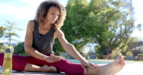 Biracial Woman Practicing Yoga Outdoors in Sunny Garden