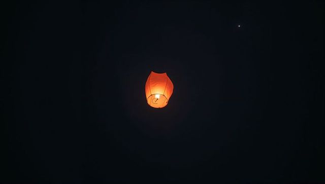 Single sky lantern ascending against starry night