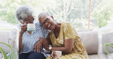 Joyful Senior Women Laughing with Coffee Indoors