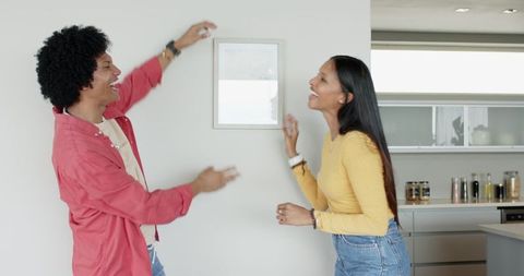 Diverse couple decorating kitchen together with joyful expressions
