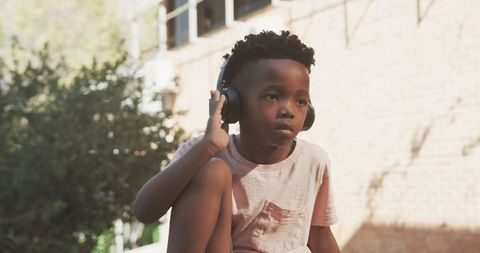 Boy Enjoys Music on Headphones During Outdoor School Break