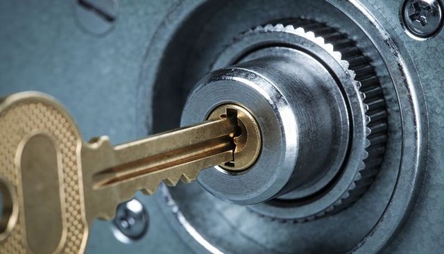 Brass key entering cylinder lock close-up, mechanical security and locksmith concept