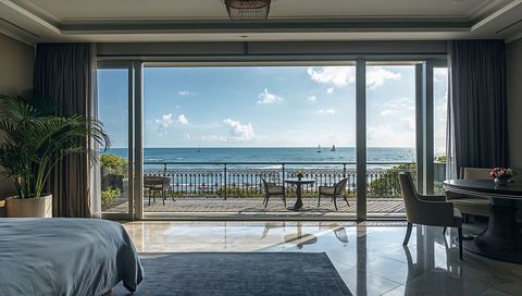 Oceanfront Luxury Suite featuring Floor-to-Ceiling Glass Doors and Sunlit Balcony Dining