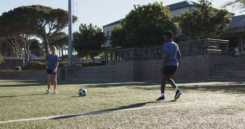 Youth friends practicing soccer on school turf during soft late afternoon light