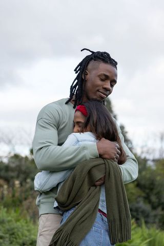 Diverse couple hugging in park, tender embrace conveying love, comfort and connection