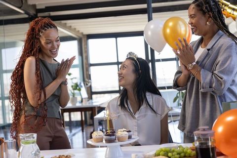 Diverse Female Coworkers Celebrating Office Birthday with Cupcakes