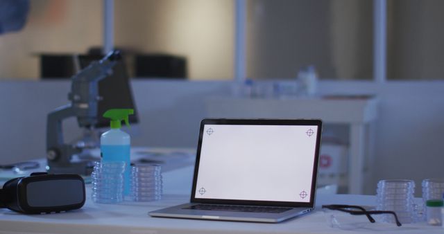 Laptop with illuminated screen at a workstation in an empty laboratory. healthcare, medical research technology and social distancing during quarantine lockdown.