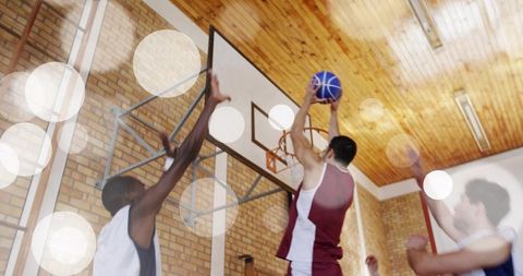 Player in Maroon Uniform Jumping Toward Hoop in Gymnasium