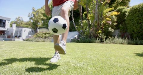 Man Juggling Football in Sunny Garden