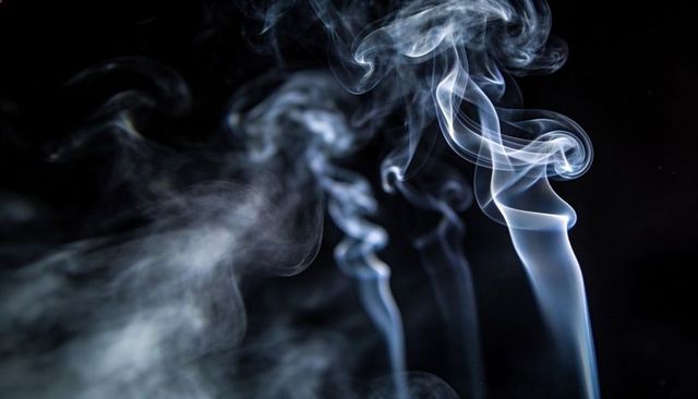 Curling translucent smoke plumes twisting, swirling over black backdrop abstract texture