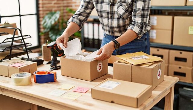 Packing orders in sunny ecommerce fulfillment workspace with labeled boxes