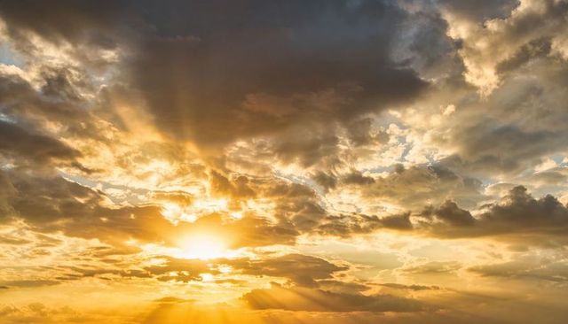 Golden sunrise with radiant crepuscular rays piercing dramatic cloudscape horizon