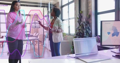 Women collaborating at interactive glass board presenting rising data graphs in office