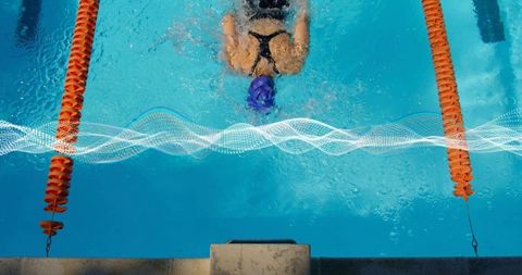 Overhead swimmer gliding through pool lane with orange dividers, training endurance and speed