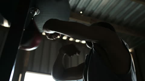 Man Practicing on Punching Bag in Gym Silhouette