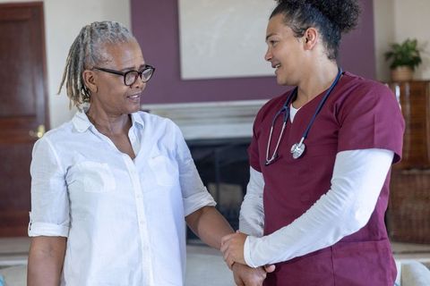 Nurse helping senior woman at home showing compassionate care and trusting connection