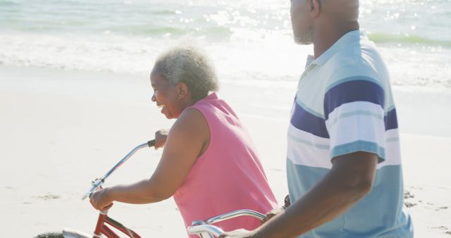 Joyful senior couple enjoying a relaxing day riding bicycles along the beach. Perfect for illustrating concepts of active seniors, retirement, health and well-being, leisure activities, bonding, and outdoor fun.