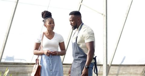 Coworkers Discussing Plant Care in Greenhouse Environment