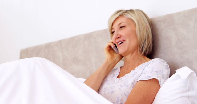 Smiling Senior Woman Relaxing in Bed While Talking on Phone - Download Free Stock Images Pikwizard.com