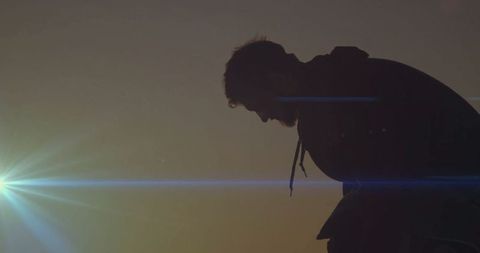 Silhouette of Hooded Man Gazing at Glowing Sunset