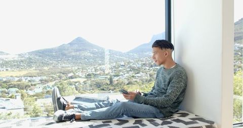 Young Man Relaxing With Scenic View Through Large Window