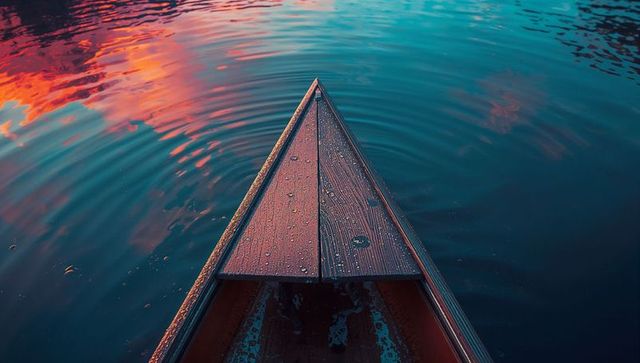 Wooden Canoe Bow Reflected in Vibrant Sunset Lake