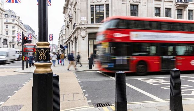 Passing blurred red double-decker bus at london crosswalk with pedestrians and union flags