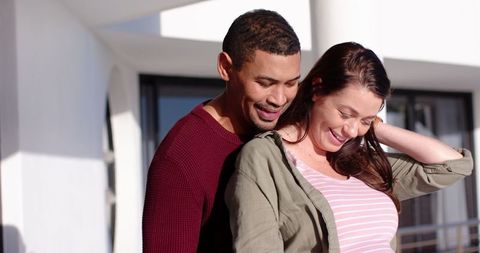 Diverse Couple Embracing on Modern Balcony Expressing Love