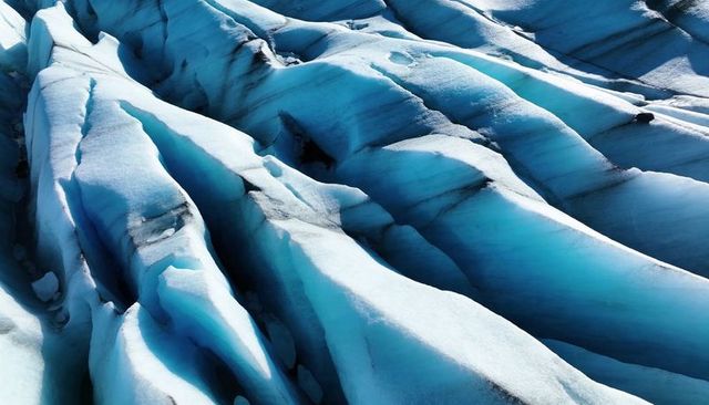 Turquoise glacier ridges revealing deep crevasses and sediment streaks
