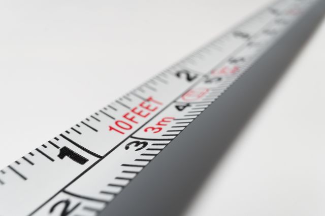 This close-up image of a measuring tape displays both metric and imperial units, offering clear markings in inches, feet, and centimeters. Ideal for use in articles or advertisements related to construction, home improvement, DIY projects, precision tools, and measurement equipment. The focus on the markings highlights attention to detail and accuracy.