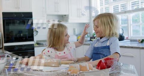 Playful siblings baking together at sunlit kitchen countertop with rolling pin and eggs