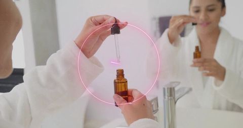 Woman using dropper for serum in chic bathroom moments