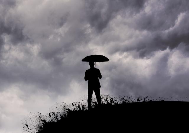 Silhouette of man holding umbrella instormy weather