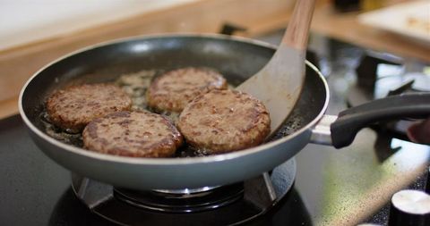 Cooking burgers in frying pan on stovetop