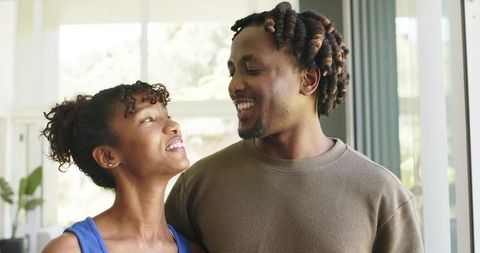Young black couple sharing warm smiles and eye contact in bright modern home interior