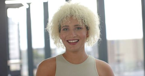 confident woman with curly hair smiling in modern office - Download Free Stock Images Pikwizard.com