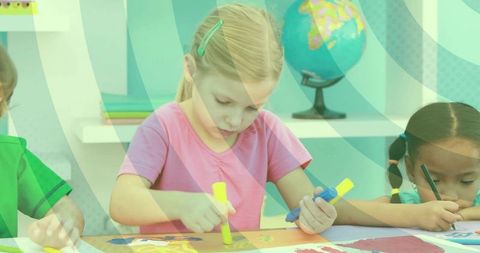 Young Girl Coloring with Markers at Colorful Classroom Table with Globe and Peers