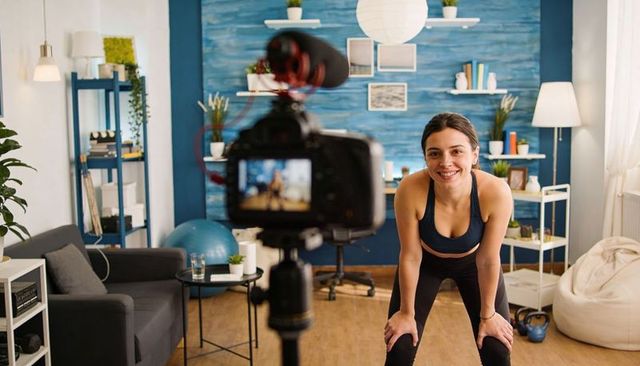 Home fitness instructor recording workout in cozy living room studio with DSLR