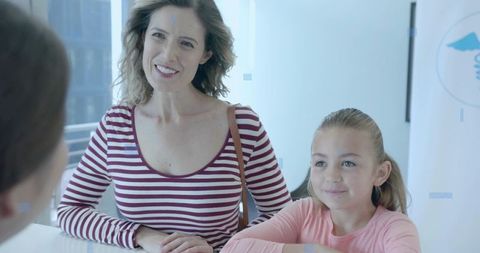 Mother and Daughter Waiting at Clinic Reception Smiling During Pediatric Medical Visit