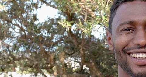 Smiling Man Enjoying Sunny Day Outdoors with Trees in Background