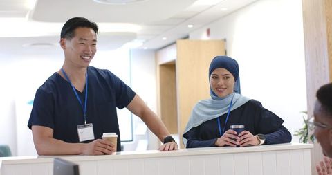 Multicultural healthcare team at clinic reception smiling and holding coffee