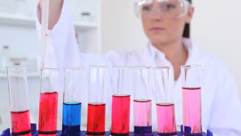 Female Scientist Performing Experiment with Colored Solutions in Laboratory