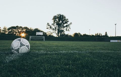 Sunset Soccer Ball on Grass with Goal in Distance Low Angle Athletic Field