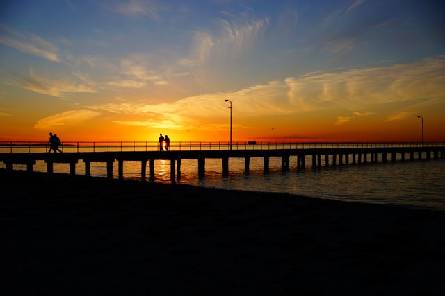 Couple Walking on Pier at Sunset with Brilliant Sky Beyond - Download Free Stock Photos Pikwizard.com