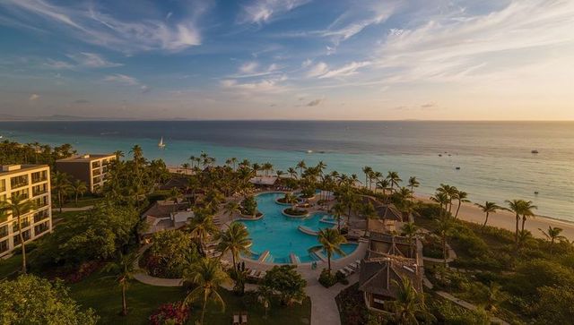 Golden sunset over circular lagoon pool at luxury beach resort with palm trees