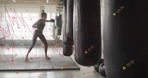 Female boxer punching heavy bag during high-tech training with performance data overlay